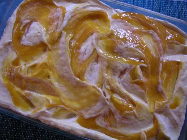 Golden pastry with swirled orange fruit filling on a cream surface, warm and inviting, soft natural light
